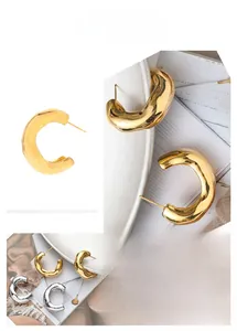 Detailed view of oversized twisted C-shape earrings in gold and silver mirror finish