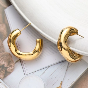 Chunky gold C-shaped earrings with irregular wavy texture in a minimalist aesthetic