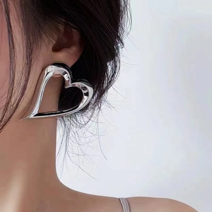 Minimalist silver-polished hollow heart hoop earrings shown on a model's ear