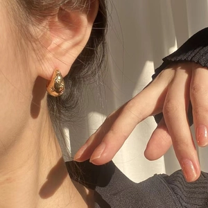 Elegant gold teardrop earrings with crystals shown on a model in natural soft light