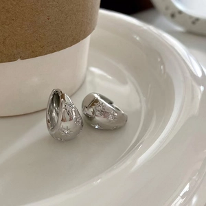Silver plated oval hoop earrings with starburst engraving and zircon on a white plate
