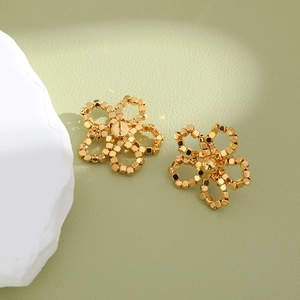 Boucles d'oreilles fleurs dorées élégantes avec texture perlée sur fond minimaliste