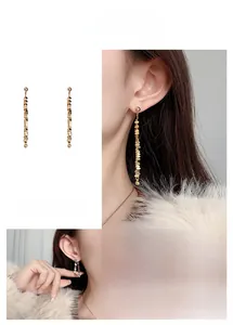 Fashionable gold-plated metal chain tassel earrings worn by a model in a lifestyle setting