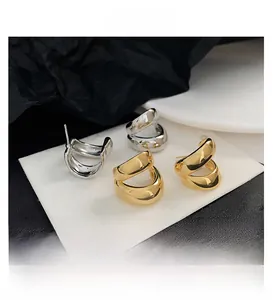 Close-up of minimalist gold and silver double-hoop earrings with high-polish finish