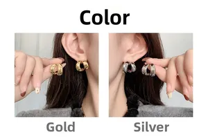 Detail view of gold and silver C-shaped minimalist stud earrings in glossy metallic finish