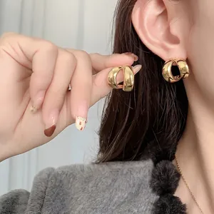 Polished gold plated chunky banana hoop earrings for women with a minimalist metallic finish