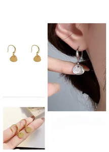Macro detail of geometric fishhook earrings in gold and silver finish with smooth metal plates