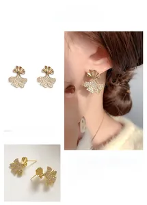 Close-up of gold ginkgo leaf earrings with pave zircon and model wearing display
