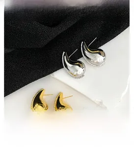 Close-up of gold and silver waterdrop earrings with micro-inlaid zircon edges