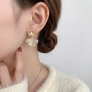 Elegant ginkgo leaf stud earrings with sparkling crystals worn by a female model