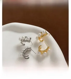 Dettaglio di orecchini geometrici placcati in oro 18K e argento con tripla perla