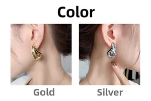 Polished chunky teardrop earrings in gold and silver finish on model showing glossy texture