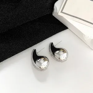 Macro shot of silver teardrop earrings with sparkling crystals on minimalist background