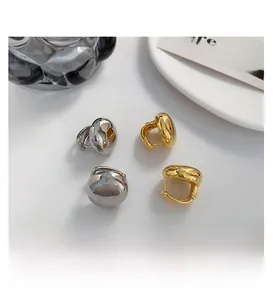 Close-up of sleek gold and silver polished metal earrings with smooth dome design