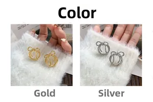 Detail view of stylish gold and silver bow stud earrings on a soft white plush background
