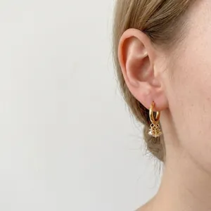 Créoles dorées élégantes avec pampilles en zircone portées de profil par un mannequin