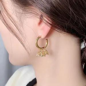 Boucles d'oreilles créoles dorées avec trois pendentifs en zircon portées par mannequin