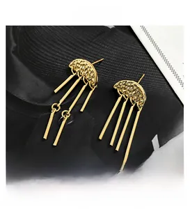 Detail of gold tassel drop earrings with hammered texture on black textured background