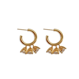 Boucles d'oreilles créoles dorées en C avec trois zircons suspendus sur fond blanc
