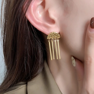 Macro shot of gold tassel earrings with hammered texture and vertical pendants