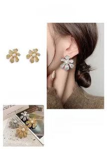 Détail macro de boucles d'oreilles fleurs plaquées or 18k avec cristaux et perle