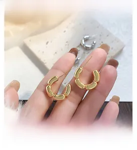 Gros plan sur les boucles d'oreilles C en plaqué or 18K avec texture unique de joint bambou