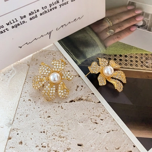 Détail des boucles d'oreilles fleur dorées 18k avec zircons pavés et perle centrale
