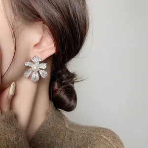Boucles d'oreilles fleurs plaquées or 18 carats avec perles et cristaux sur un mannequin