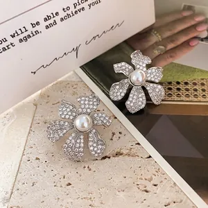 Boucles d'oreilles fleurs argentées avec cristaux et perles sur fond de pierre naturelle