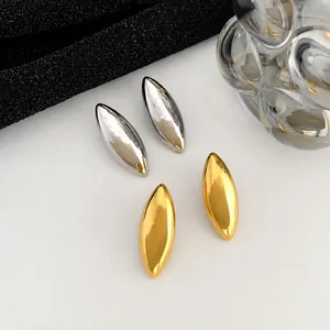 Macro detail of minimalist canoe-shaped geometric stud earrings in gold and silver