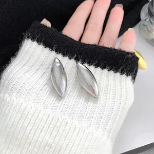 Orecchini geometrici in argento lucido presentati su un polsino di maglia