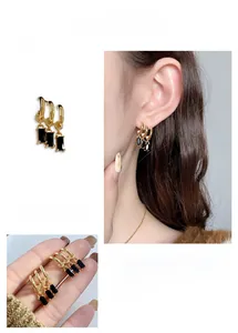 Detail of 18K gold plated C-shape fringe earrings with black rectangular zircon pendants