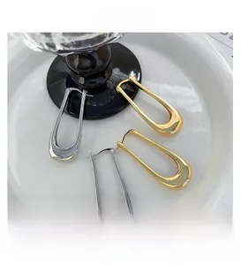 Close-up of minimalist gold and silver U-shaped hoop earrings with polished metal finish