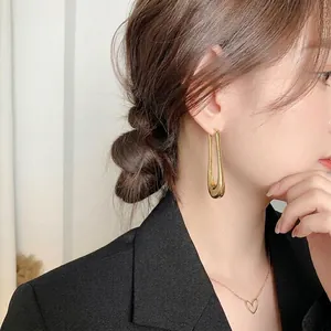 Polished gold U-shaped drop earrings for women worn by a model in a minimalist style