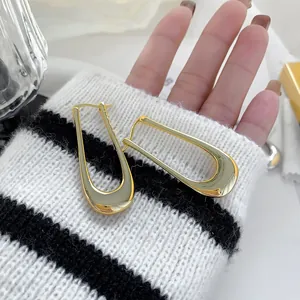 Detailed close-up of 18K gold-plated U-shaped hoop earrings with a polished glossy finish