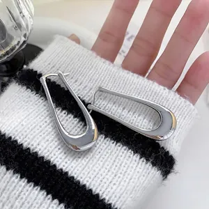 Polished silver U-shaped earrings displayed on a striped knit cuff for a modern look