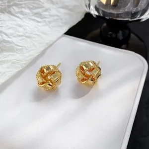 Macro shot of 18K gold-plated woven sphere stud earrings on white jewelry pad