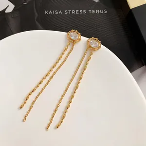 Boucles d'oreilles pendantes dorées 18 carats avec zircons scintillants sur plateau blanc
