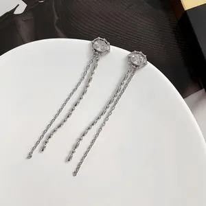 Gros plan de boucles d'oreilles pampilles argentées avec cristaux et perles sur plateau blanc
