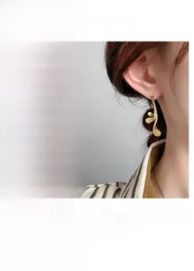 Close-up of curved leaf earrings with 24K gold plating and cubic zirconia inlay