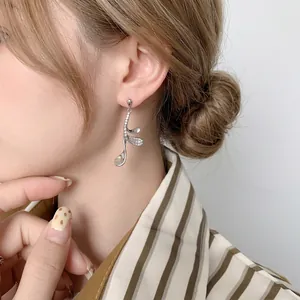 Silver leaf earrings with cubic zirconia and 24K gold plating on an elegant model
