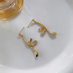 Elegant 24K gold plated leaf earrings with sparkling cubic zirconia on white ceramic plate