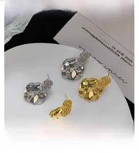 Detailed macro view of gold and silver irregular lava texture earrings on a white tray