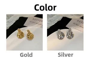 Detailed close-up of irregular hammered texture metal stud earrings in gold and silver