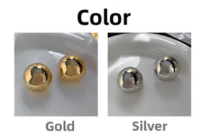 Polished gold and silver ball stud earrings displayed on a white ceramic dish