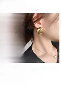 Detail view of mirror-polished dome stud earrings in gold and silver plating