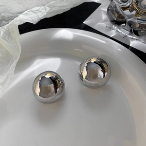 Macro shot of polished silver spherical stud earrings with a glossy mirror finish texture