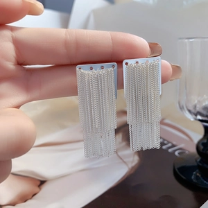 Detailed view of elegant silver-colored long tassel chain drop earrings in a lifestyle setting
