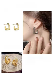 Détail de boucles d'oreilles géométriques en C à couches en placage d'or 24 carats poli