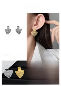 Detail of irregular triangular earrings with hammered texture in gold and silver finish